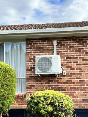 An air conditioning unit on the side of a brick house